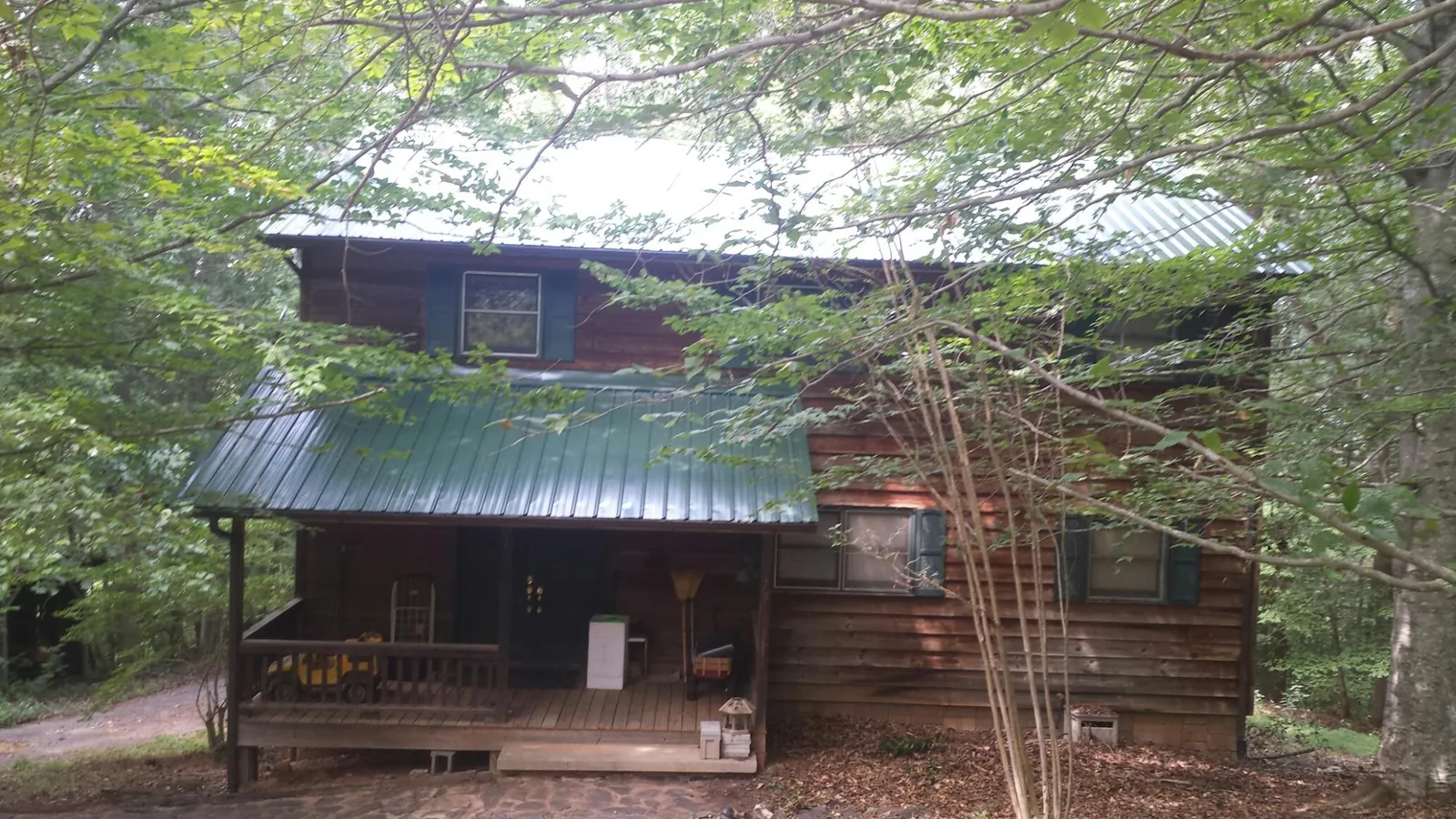 Green metal roof and covered porch on a log cabin in Cliff Island