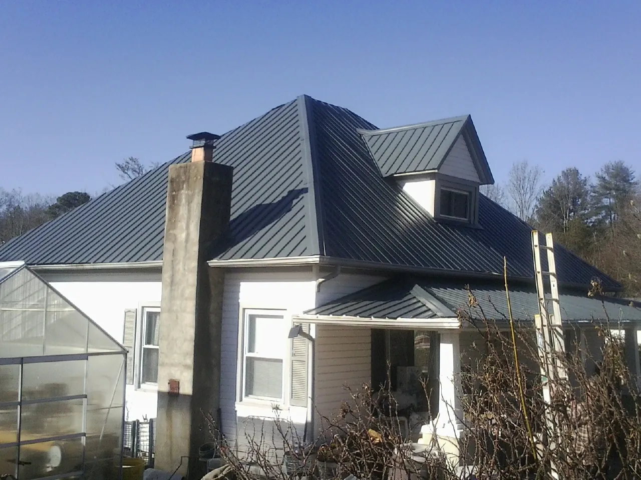Dark blue standing seam metal roof on a white farmhouse with dormer — Slate & Tile Roof Repair by Roofing Brothers in Cliff Island