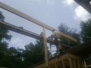 Carpenter setting a ridge beam over a new addition frame — Ice Dam Removal by Roofing Brothers in Cliff Island