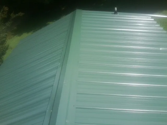 New green metal panels meeting at the ridge of a roof — Flat Roof Repair work by our crew in Cliff Island