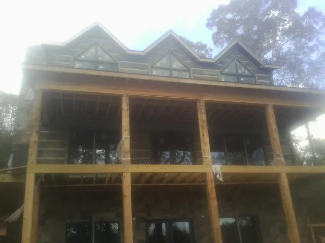 Dormers and porch framing on a large log home under construction — Roof Coating work by our crew in Cliff Island