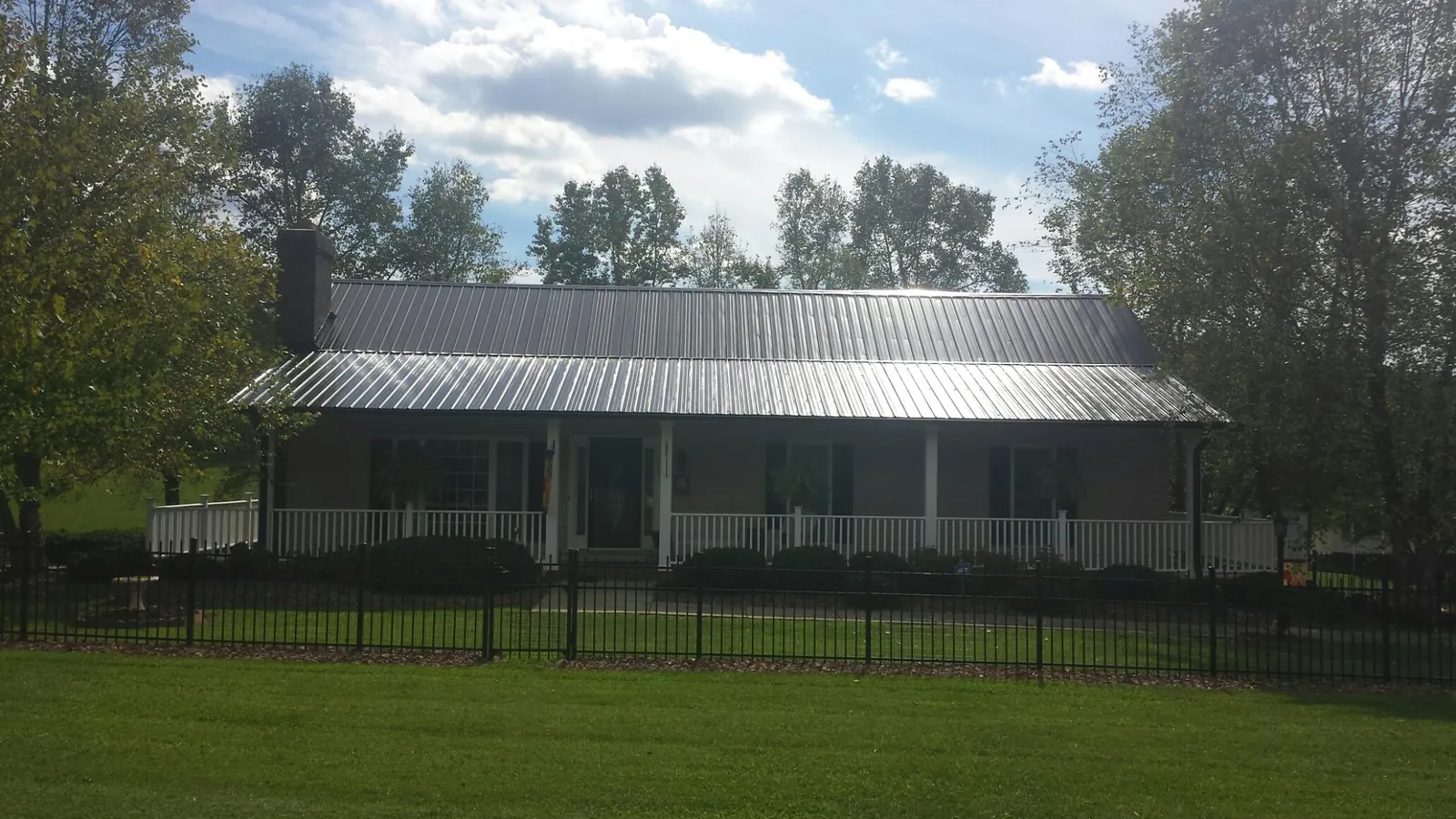 Gray metal roof on a brick ranch with a full width front porch — Gutter Guard Installation work by our crew in Cliff Island