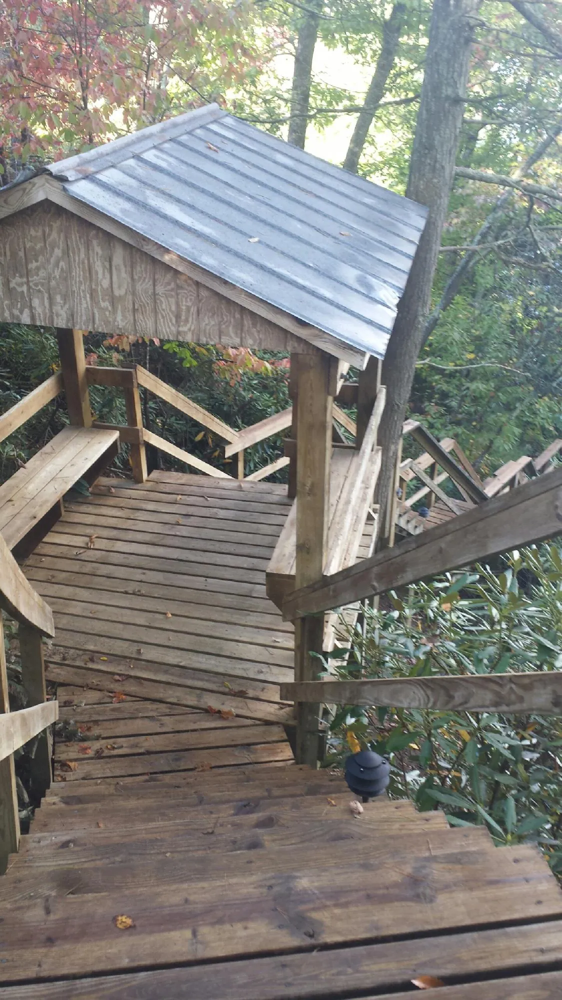 Metal roofed shelter over wooden steps on a wooded walkway — Skylight Repair & Installation work by our crew in Cliff Island