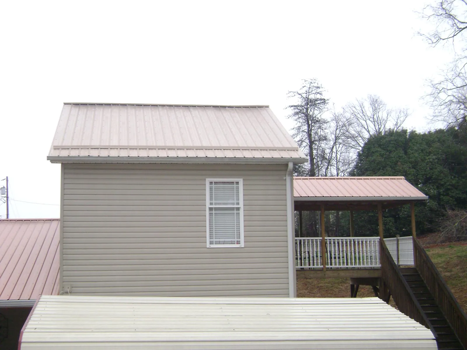 Tan metal roofs on a two story addition and attached porch, from a Roof Replacement job in Cliff Island