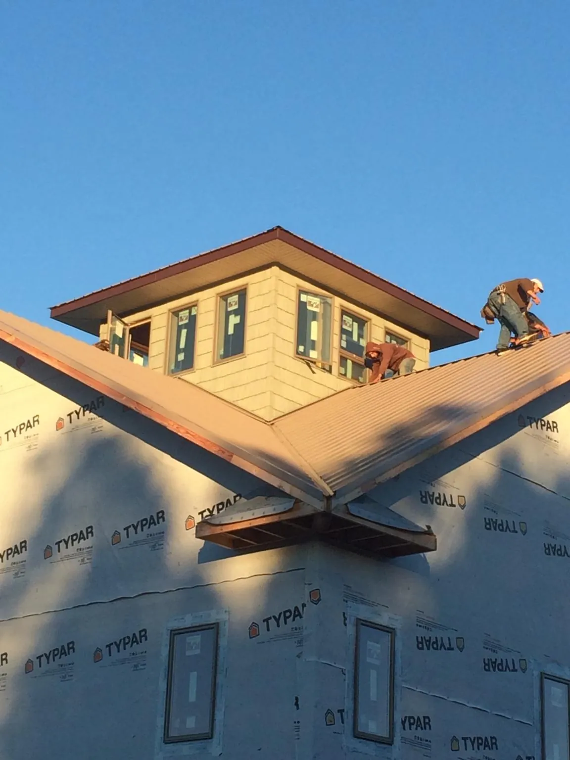 Roofers working around a rooftop cupola on a new metal roof at sunset — Roof Waterproofing in Cliff Island by Roofing Brothers
